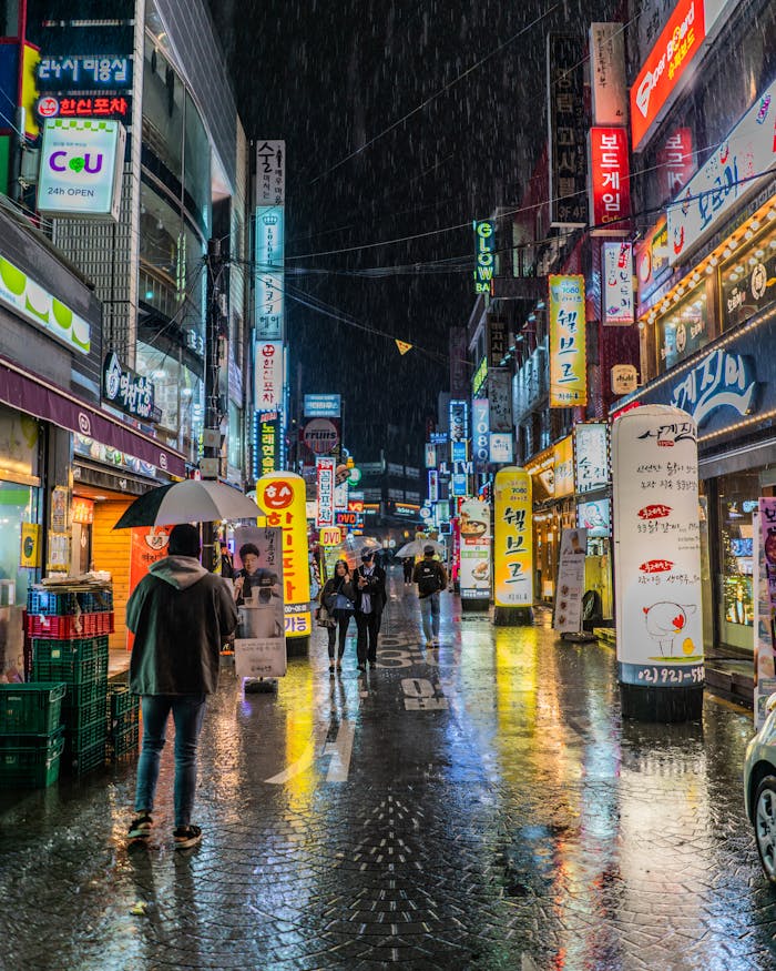 Colorful neon-lit street in Seoul, South Korea showing bustling nightlife with reflections on wet pavement.
